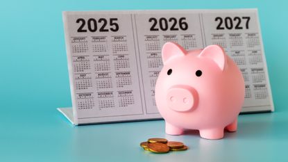 A piggy bank standing in front of a calendar for 2025-2027 and a pile of coins on a light blue background