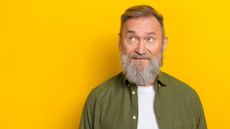 Portrait of thoughtful bearded mature man against a bright yellow background