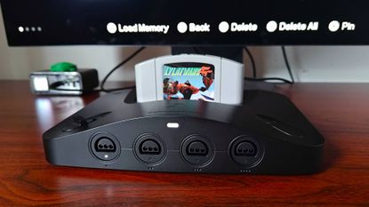 Close up of Analogue 3D on woodgrain desk with Star Fox 64 (Lylat Wars) cartridge inserted and monitor in backdrop with new Memories save states feature active.