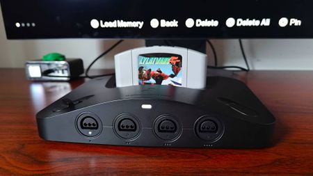 Close up of Analogue 3D on woodgrain desk with Star Fox 64 (Lylat Wars) cartridge inserted and monitor in backdrop with new Memories save states feature active.