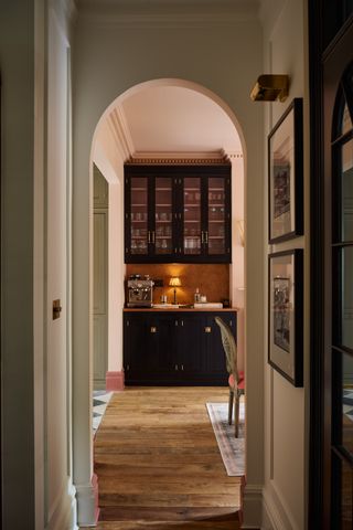 Archway leading into kitchen with dark colored cabinets