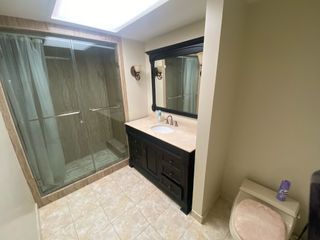 A bathroom with a dark wooden cabinetry and large shower