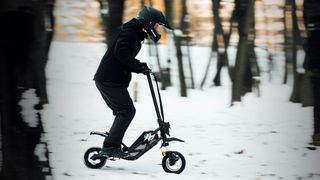 Man wearing a helmet rides an Acer Predator scooter on snowy terrain.