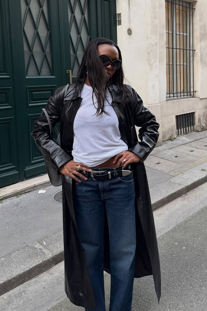 a woman wearing a white T-shirt, indigo blue jeans, and a black leather coat