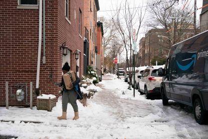 An Amazon delivery driver carries a package through the snow following a winter storm in Philadelphia, Pennsylvania, U.S.