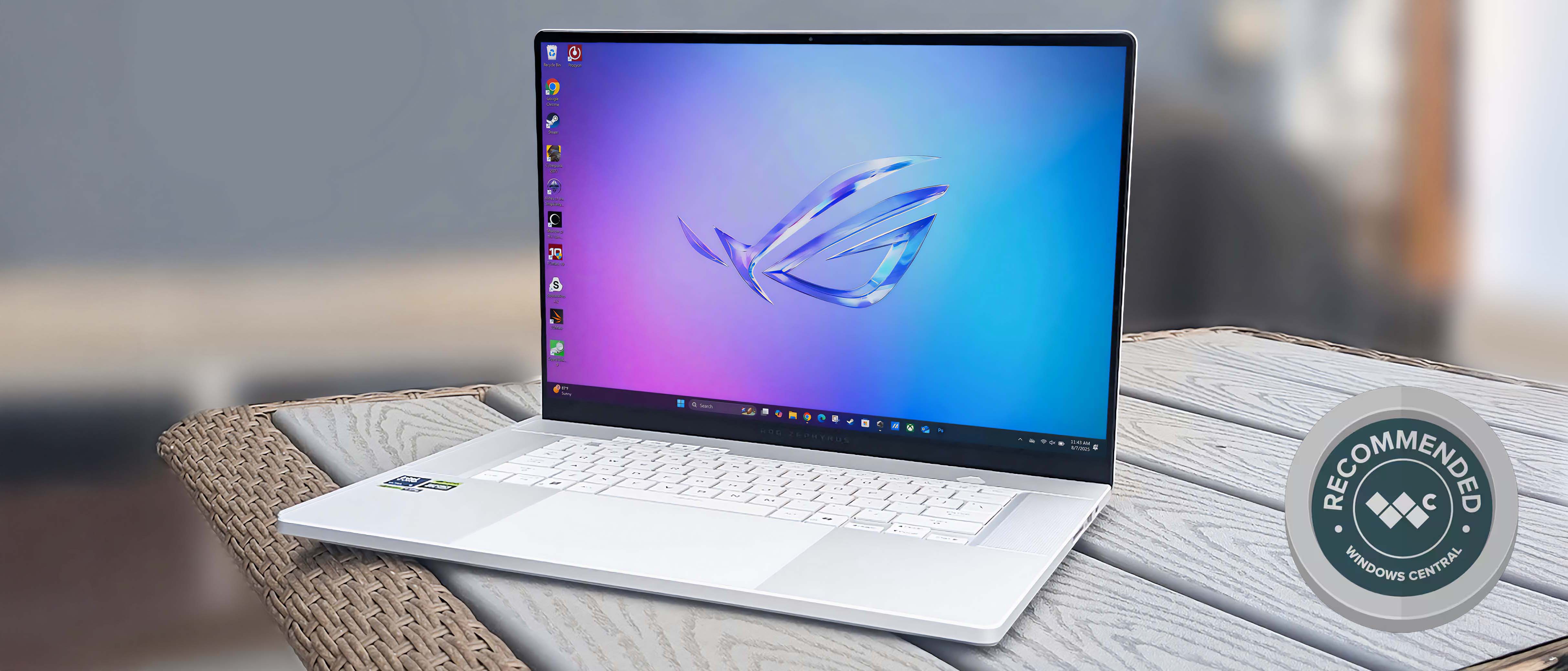 ASUS ROG Zephyrus G16 outside on a grey table. It has a vibrant screen displaying purple and blue hues with the ROG logo in the middle. 
