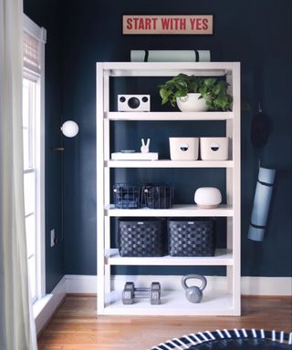 A dark blue living room with white storage unit with fitness-related items