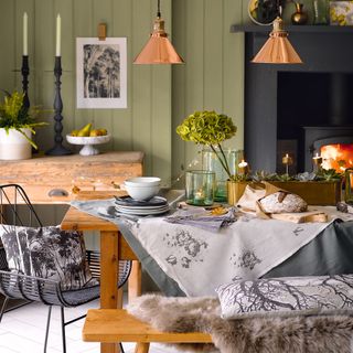 Country-dining-room-with-green-panelled-walls,-copper-lighting-and-rustic-furniture