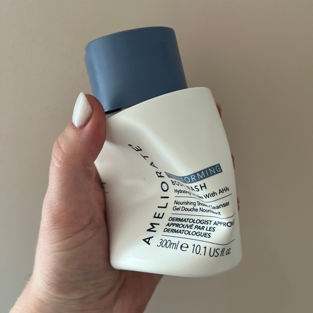 Hand holding empty bottle of Ameliorate Transforming Body Wash