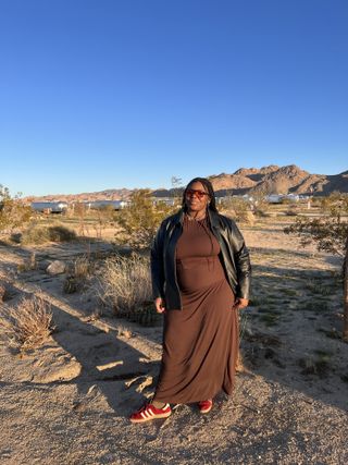 chichi wears brown tank and skirt set with black leather jacket and red sneakers and aviator sunglasses in the desert
