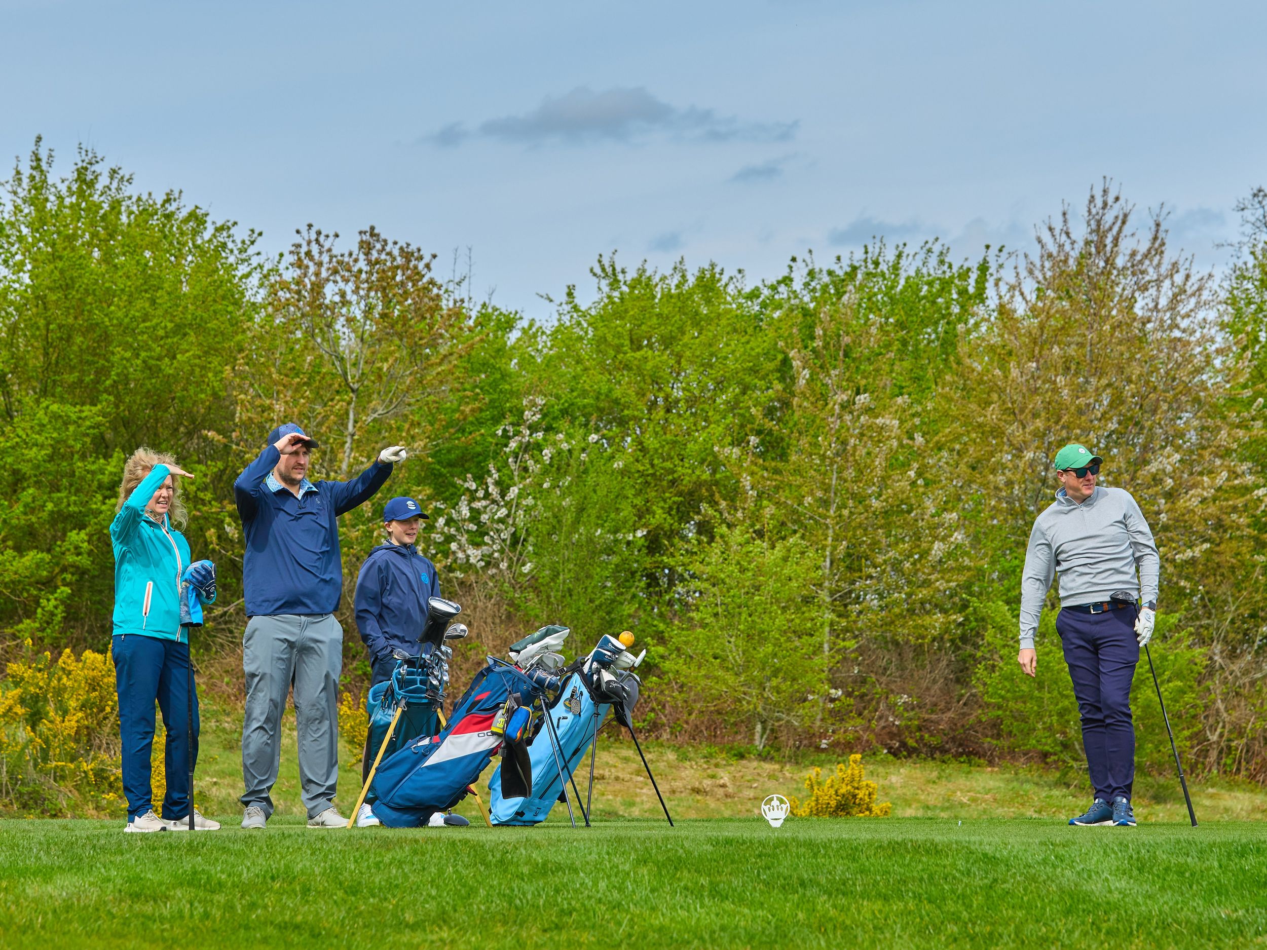 Group of golfers on a tee trying to see where a tee shot has gone