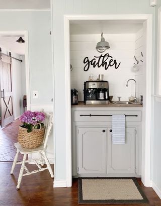 Coffee nook with grey kitchen cabinets, coffee maker and silver handle detail