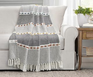 A Lush Decor Fall Tassel Throw Blanket on a gray sofa