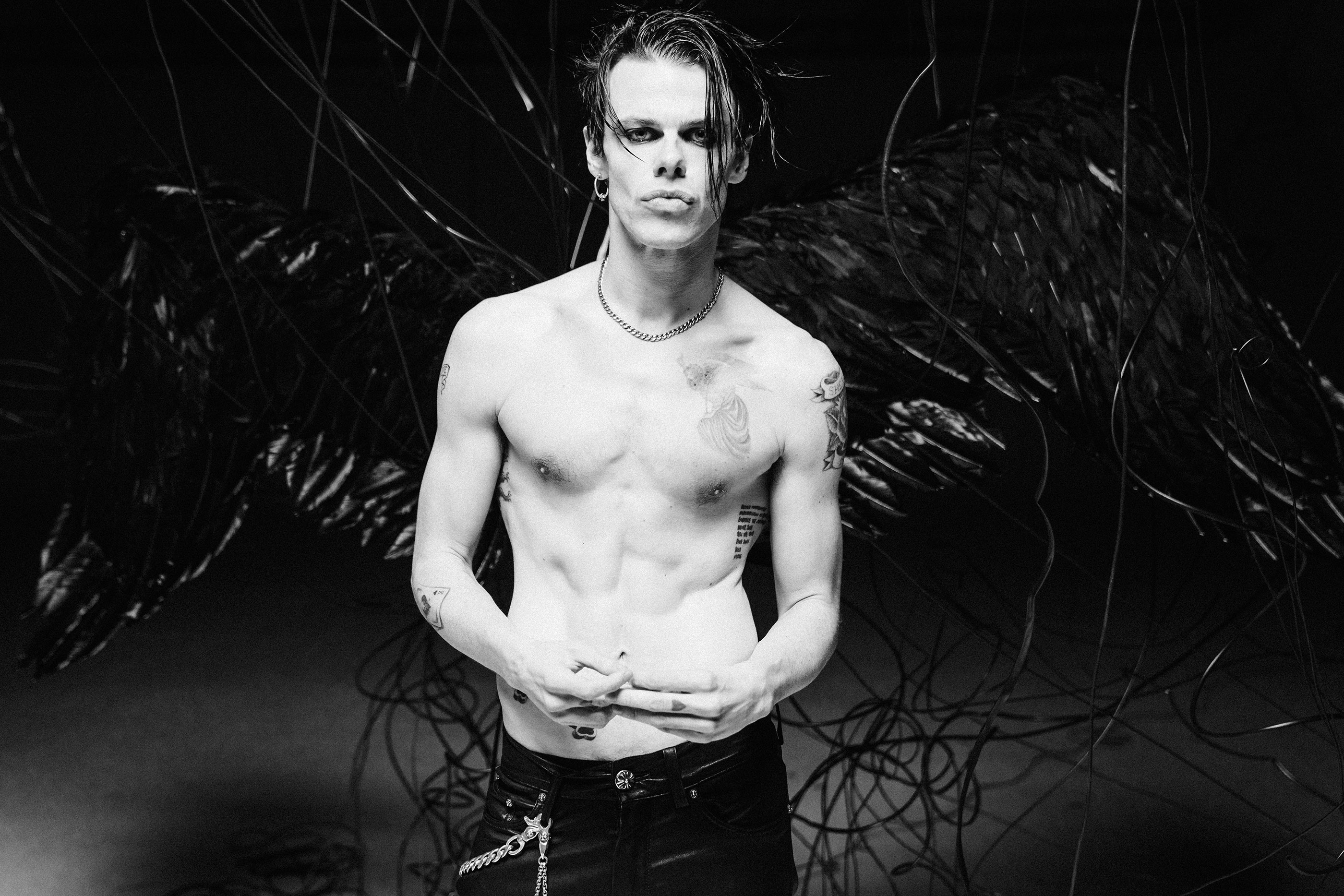 A portrait of Yungblud looking into the camera. He is shirtless with a serious expression