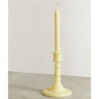 yellow candle in a traditional tall candlestick design
