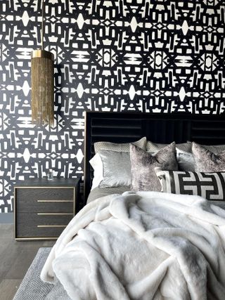 A bedroom with a black and white wallpaper and monotone furnishings