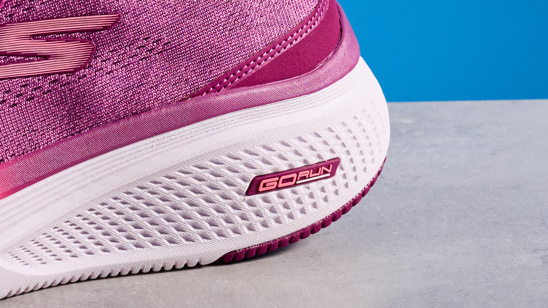 the skechers go run elevate 2.0 running shoes in the women's style, in fuchsia pink, photographed against a blue background