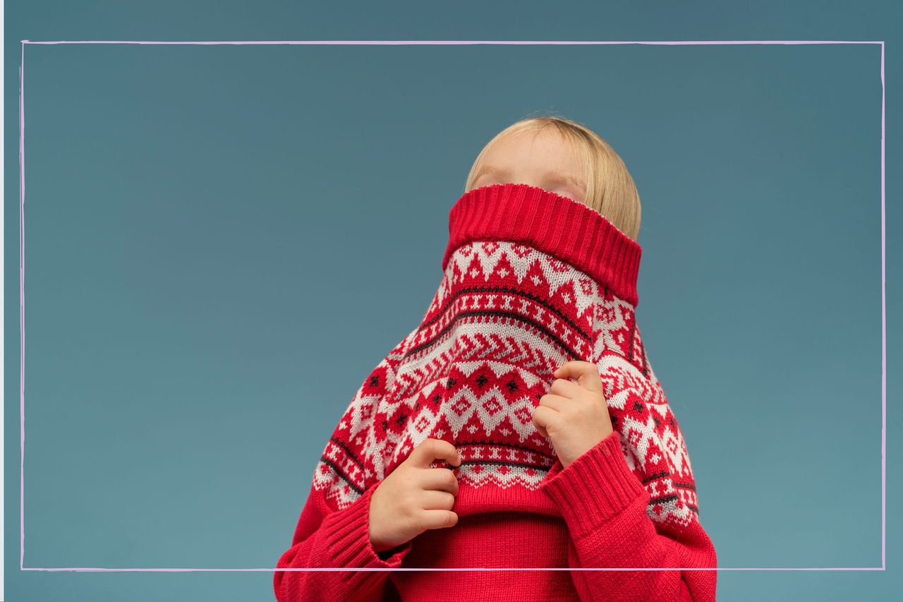 child pulling on a jumper over their head