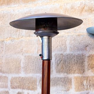 Closeup of gas patio heater against brick wall