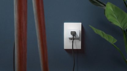 WeMo WiFi Smart Plug plugged into white socket against dark navy wall