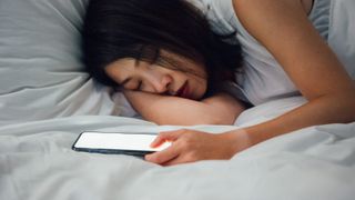 woman sleeping next to smartphone