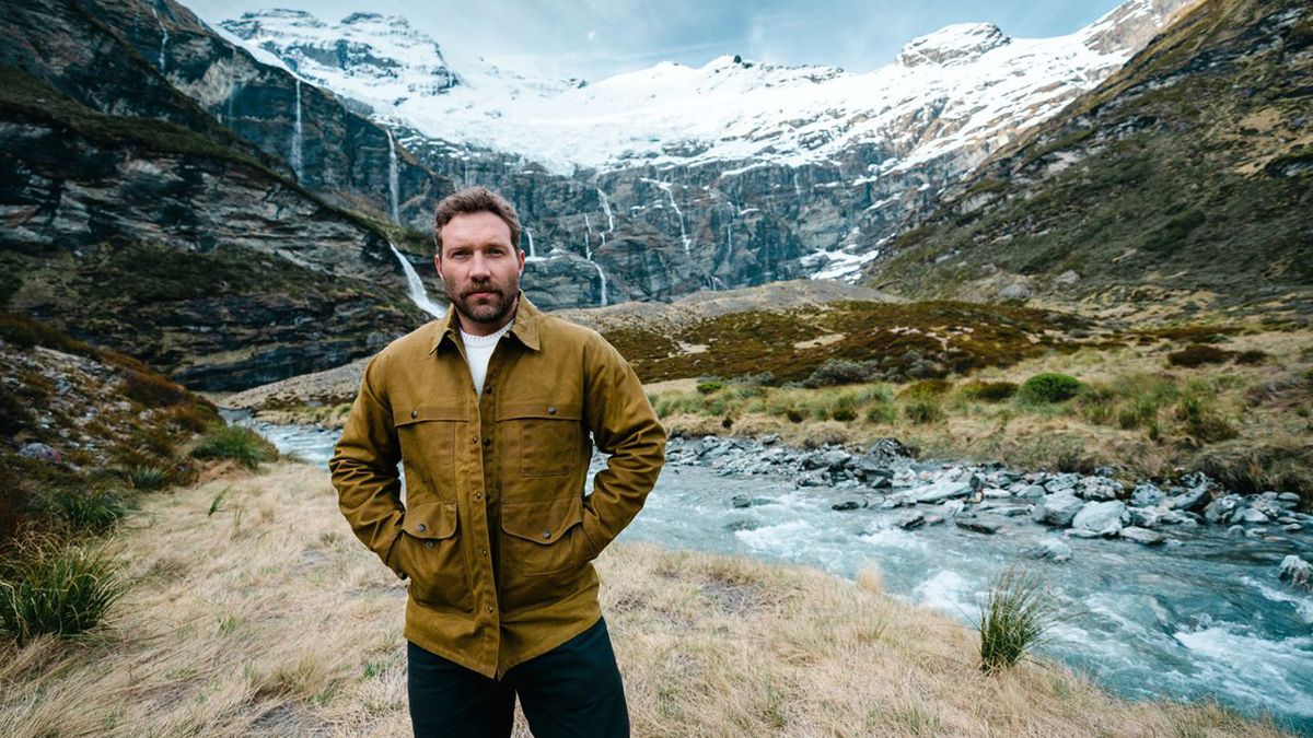 Jai Courtney standing in front of a mountain in New Zealand.