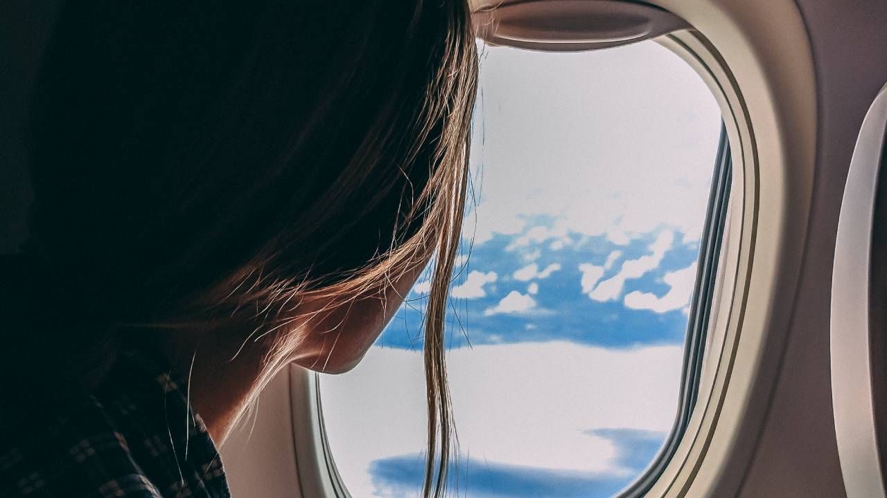 Travel gadgets, woman looking out from a plane window