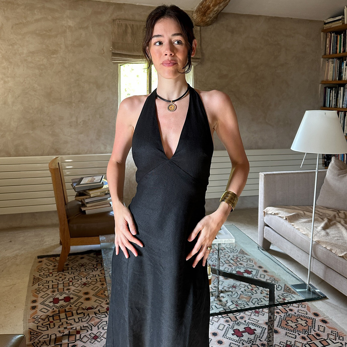 Ilana wears a black dress, the row emi sandals, and a necklace.