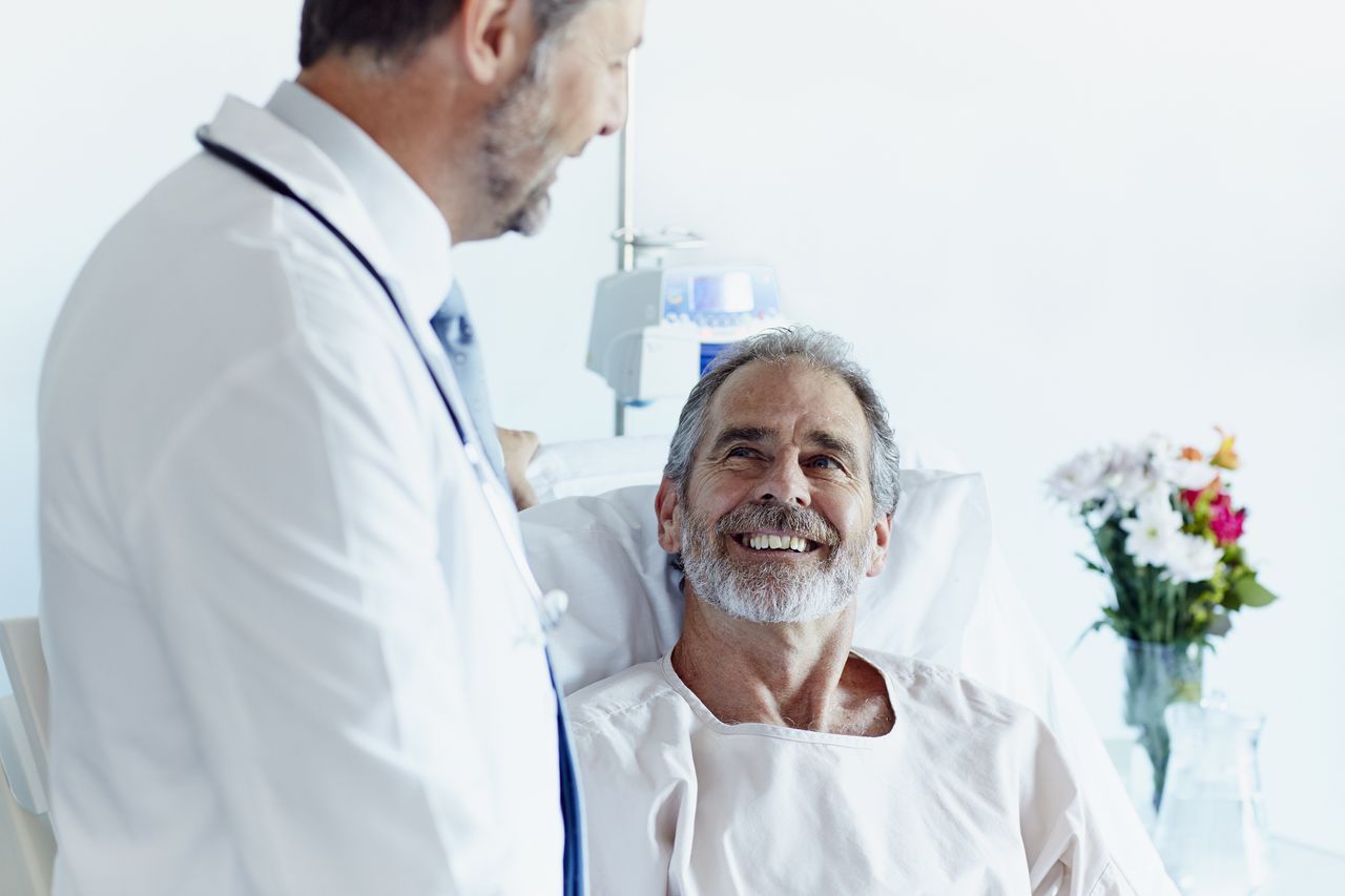 Happy mature patient looking at male doctor in hospital ward