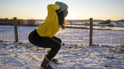Attractive woman wearing knit hat practicing squats during winter
