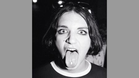 Brian Molko from Placebo with an asprin (possibly) on his tongue in black and white