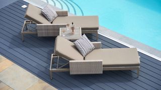 swimming pool with dark coloured deck and cream sun loungers