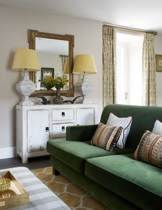 living room with green couch, sideboards with two matching table lamps and mirror
