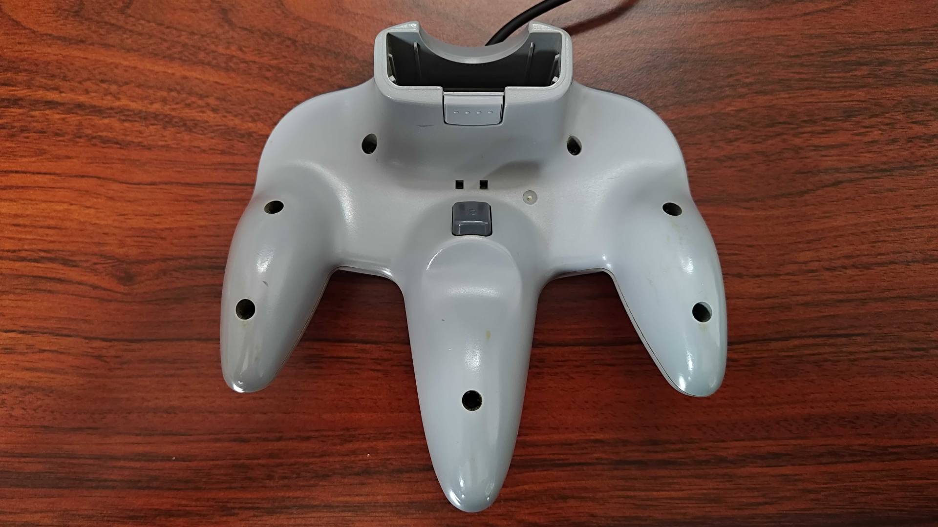 Back view of N64 controller on woodgrain desk.