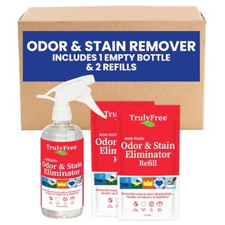 Two red stain remover cleaner packets, with a matching spray bottle. In front of a cardboard box. 