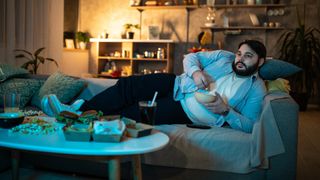 Man lying on couch eating