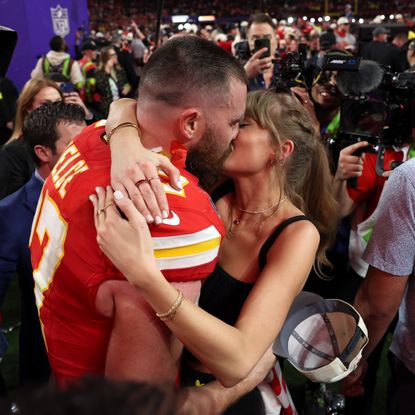 Taylor Swift wearing red lipstick while kissing Travis Kelce at the 2024 Super Bowl.