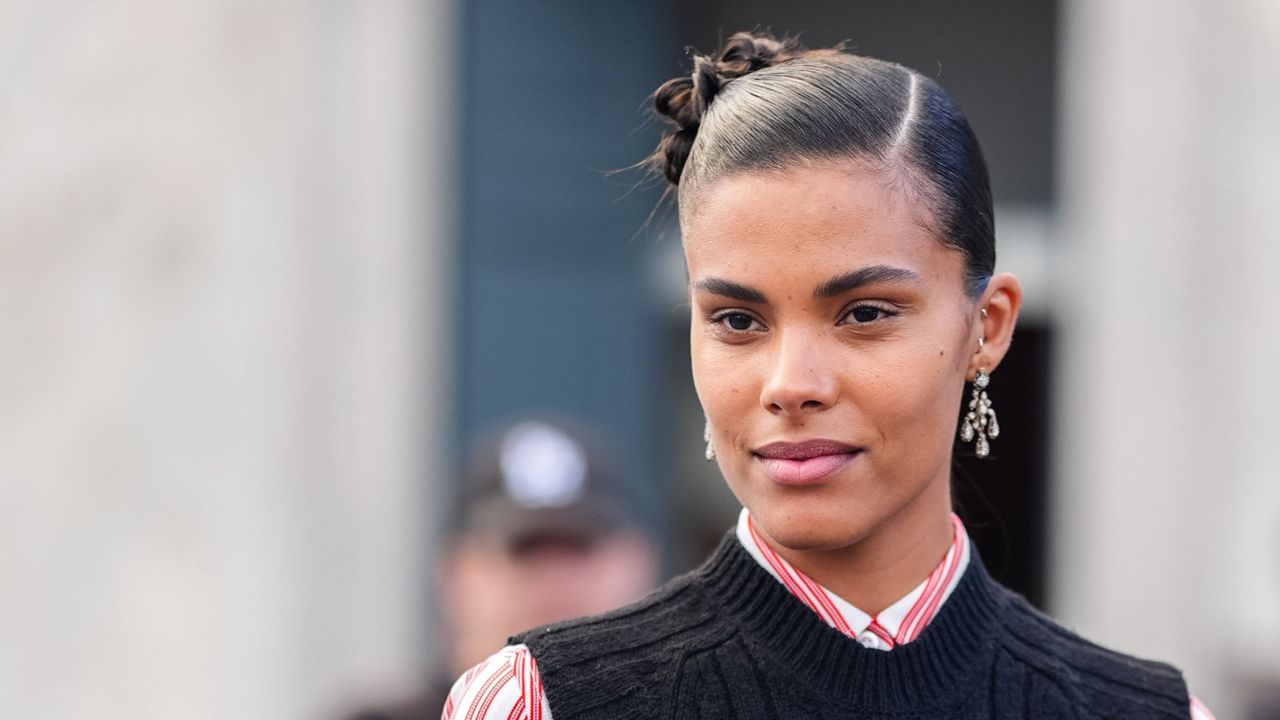 glossier boy brow arch - Tina Kunakey is wearing a red and white shirt under a navy knit top with defined brows