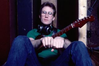 Portrait of American Rock musician Marshall Crenshaw, headphones around his neck and a guitar in his lap, as he sits crosslegged on the floor at the Record Plant Recording Studio, New York, New York, January 27, 1982. He was there to record his debut album, 'Marshall Crenshaw'. 