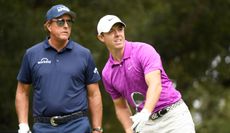 McIlroy watches his tee shot whilst Phil Mickelson watches on
