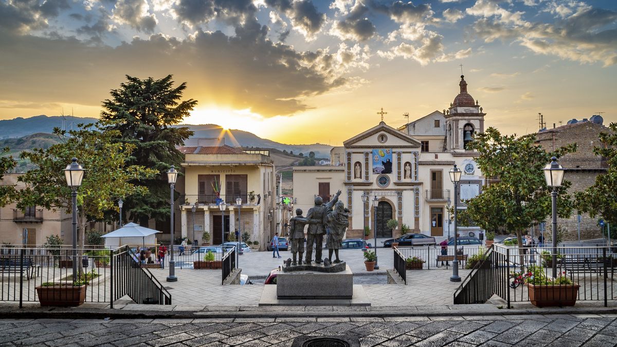 Photograph taken of an old building in Palermo, Italy, with the sun setting in the background over the hills