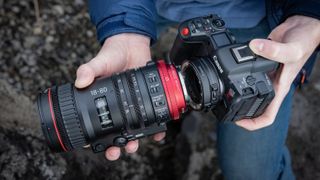 Hands holding the Canon EOS R5 C camera and a lens