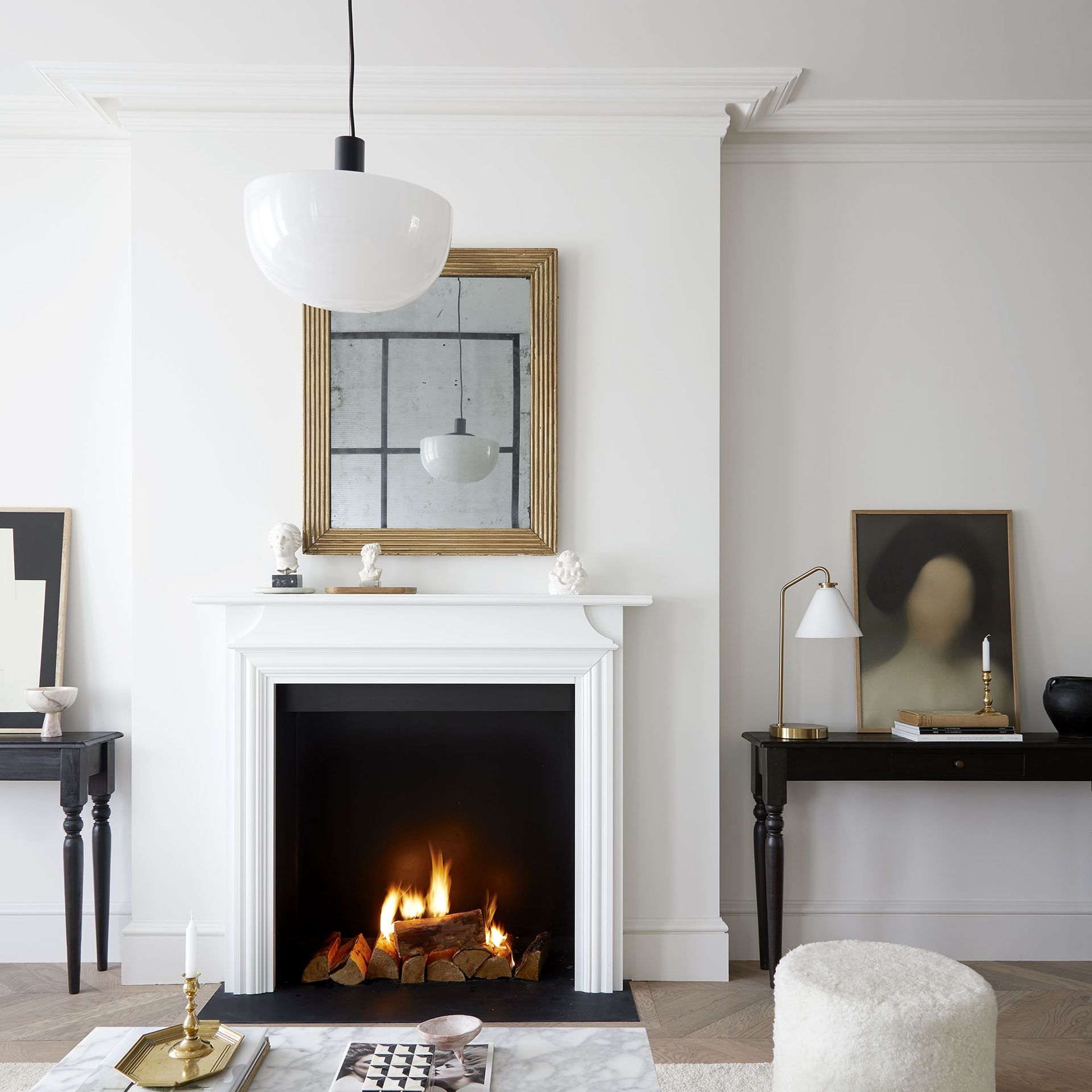 White living room with fireplace, mantle mirror and boucle pouffe.