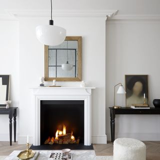 White living room with fireplace, mantle mirror and boucle pouffe.