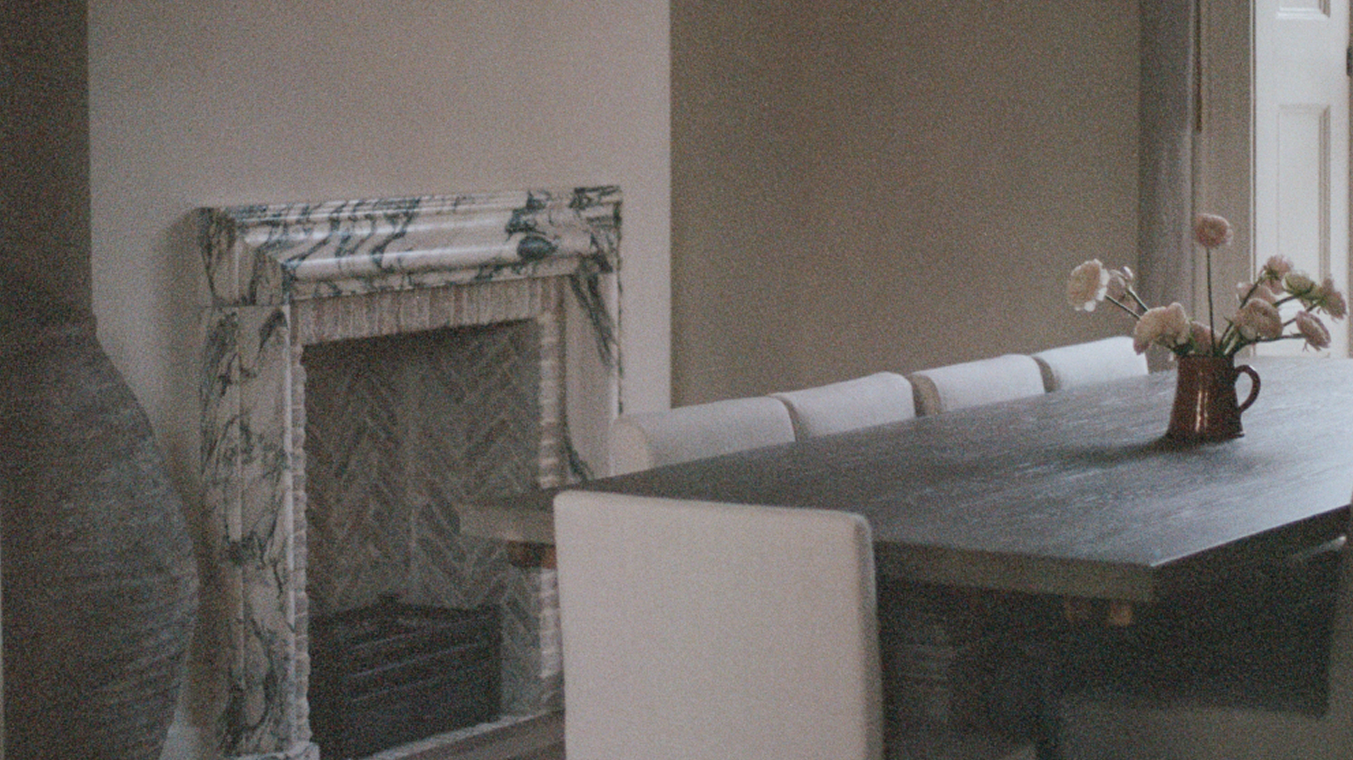 oak dining table with linen chairs and marble fireplace