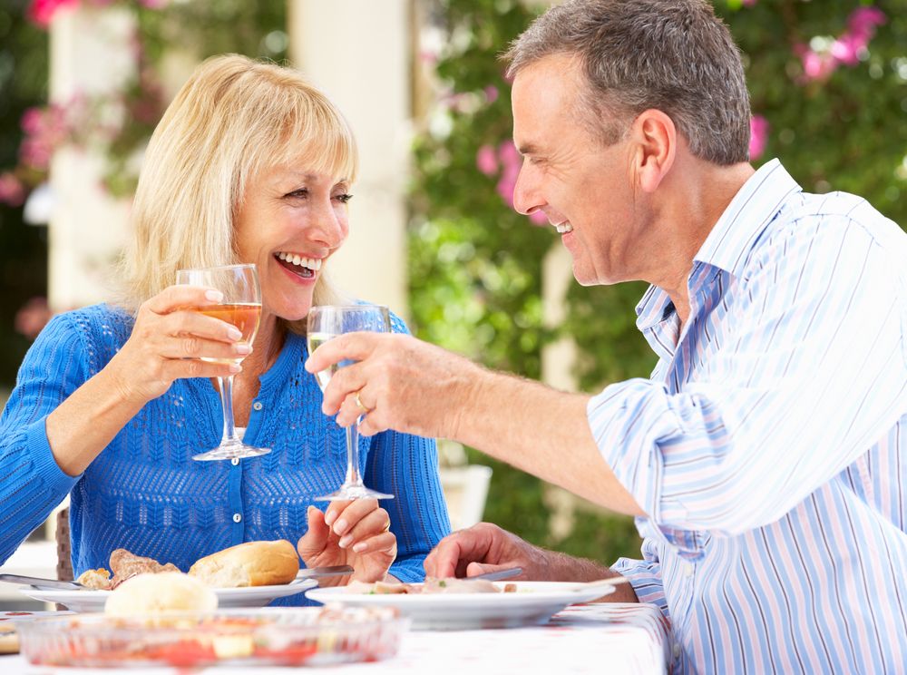 An older couple toasts with glasses with wine.