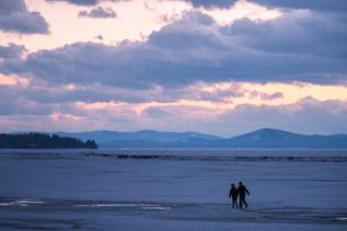 A couple walks across the ice on frozen Lake Champlain in Burlington, Vermont.