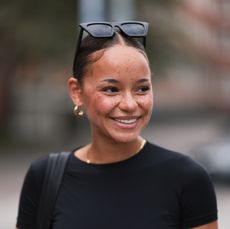 Naomi Amissah seen wearing black sunglasses, gold earrings and necklace, black cropped shirt, black structured leather shopper bag, on August 25, 2023 in Hamburg, Germany.