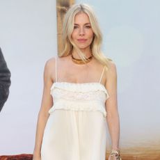 Sienna Miller wears a white dress and black boots.