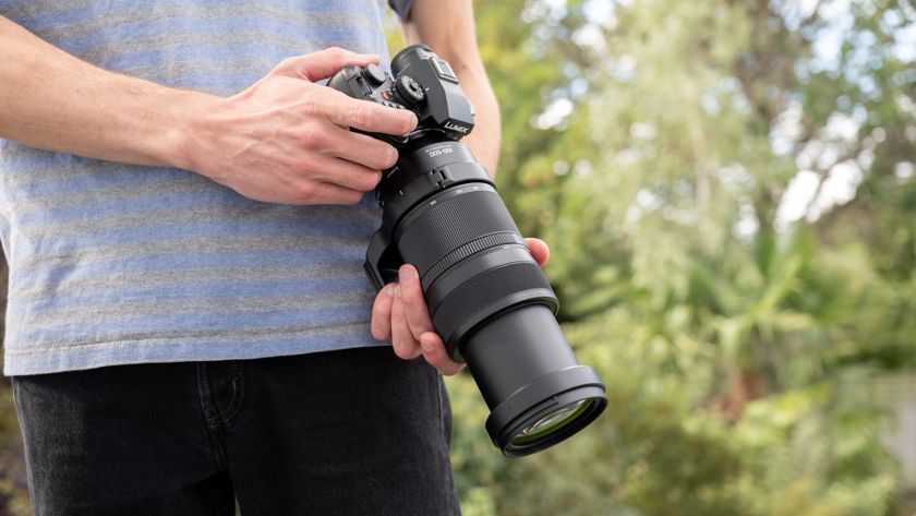 Panasonic Lumix S1II camera with a Lumix S 100-500mm f/5-7.1 lens attached held in a pair of hands outdoors